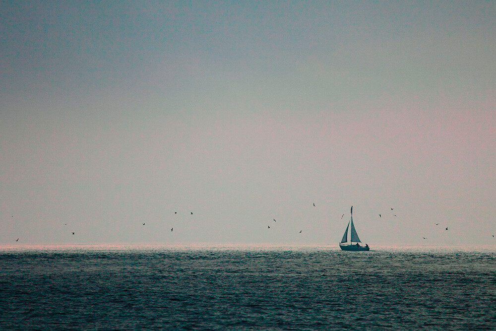 In this image, I had a flat gray mist killing any interest in the sky. But when this lone sailboat began sailing right at the edge of the mist, I began to see possibilities. By placing the sailboat at the intersection of the rule of thirds, and placing the horizon line at the bottom third of the image, I allowed the negative space to take up a lot of room. That negative space gives the boat a place to go, and keeps the interest squarely on the sailboat.