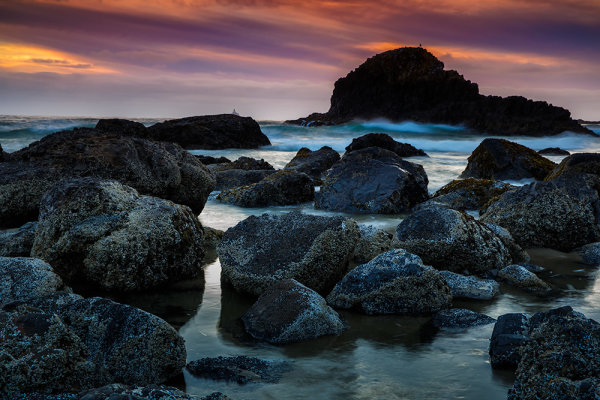 Indian Beach features a rocky area along with a wide expanse of sand.  On this day, gray clouds had been hanging around all day, keeping the light pretty flat and boring. Just as the sun began to set, the layers of clouds separated and began reflecting this unbelievable color. To capture it, I used both a 3 stop hard edged graduated neutral density filter, stacked on top of a hard edged 4 stop graduated ND. That brought out the color nicely and allowed me to maintain good detail in the foreground. 1/15, f/16, ISO 400. EOS 5D Mark III, EF 24-70 f/2.8L II at 50mm. 