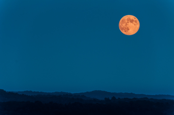 Don't just place the moon in an empty sky, including a foreground object will create a more dramatic image.