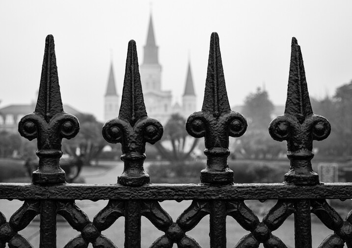 Close up of iron fence around Jackson Square in New Orleans with the St. Louis Cathedral behind.