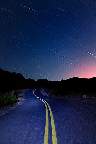 This image was created as a single exposure. Exposure time was 30 minutes, ISO 100, f/5.6. The star trails are dimmer due to the smaller aperture, the fact that the moon was still in the sky, and light pollution from the city in the distance, seen as the glow to the right.