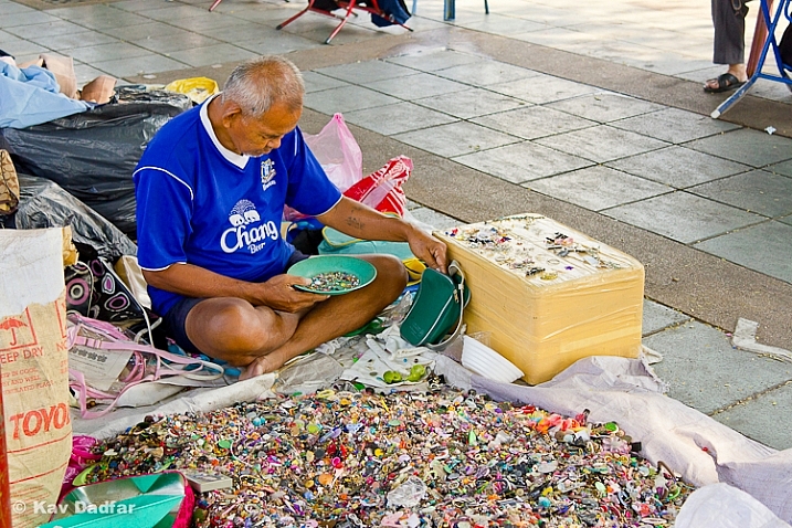 Man selling buttons in a market by the side of the road in Bangkok.