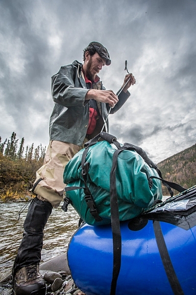 Securing well-sealed dry bags to the front of a packraft, a daily chore on a remote river trip.