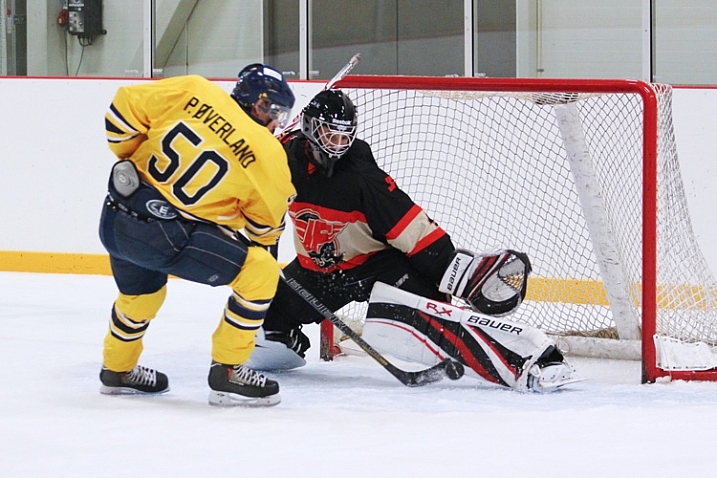 A hockey player tries to deke around the goaltender