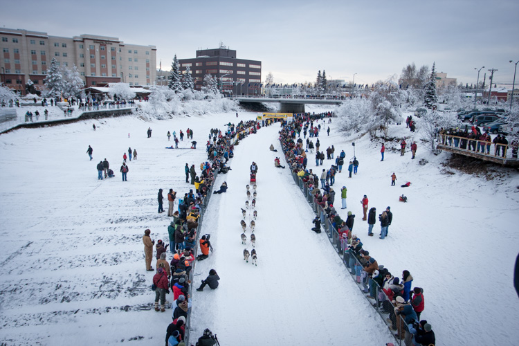 This broad perspective is also an effective way to tell the story, showing the rows of spectators and the buildings of Fairbanks in the background.